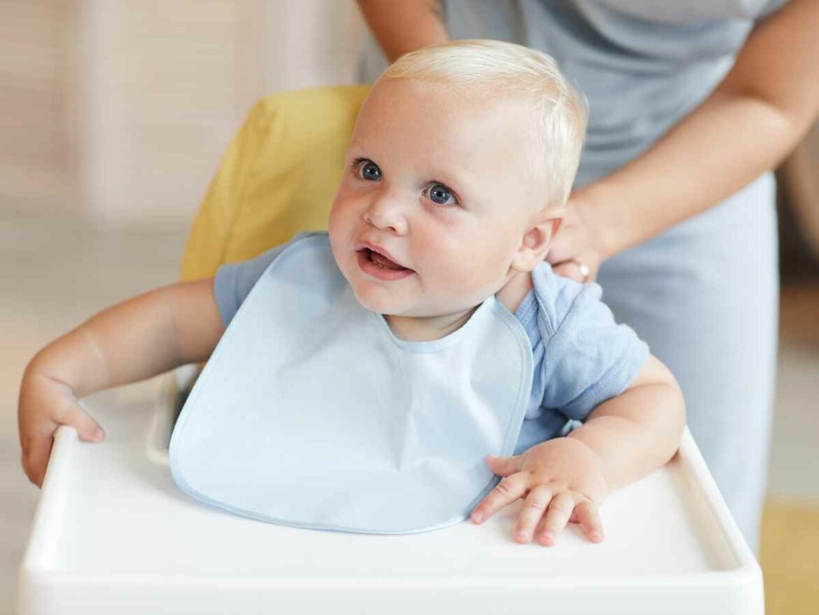Mãe amarrando babador em seu bebê de poucos meses.