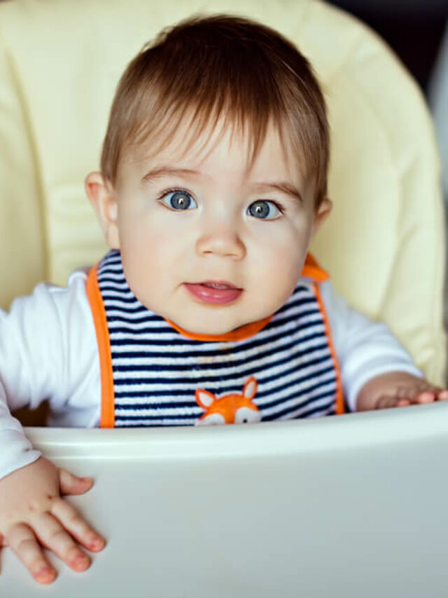 Bebê usando babador enquanto espera sua comida em seu cadeirão