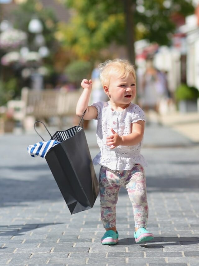 Bebe segurando uma sacolas com suas novas roupas estilosas.