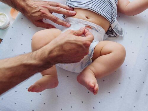 Cuidador limpando um bebê de forma correta durante a troca de fralda, utilizando movimentos suaves e higiênicos, garantindo o conforto e a saúde do bebê com atenção e carinho.