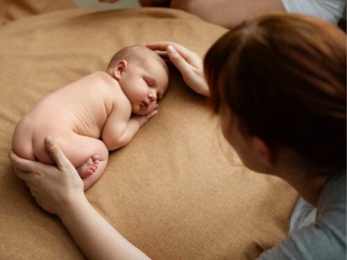 Fotógrafa posicionando cuidadosamente um recém-nascido para uma sessão de fotos newborn, ajustando a pose com delicadeza e atenção.