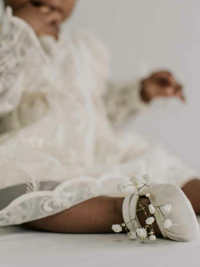 Neném vestindo roupa de batizado e sapatinho, escolhidos pela mãe.