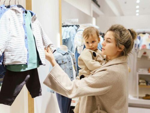 Gestante em uma loja escolhendo com carinho a roupa de batismo para seu filho.