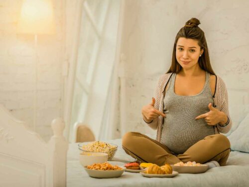 Grávida cercada por carboidratos integrais que fazem parte da alimentação para gestante.