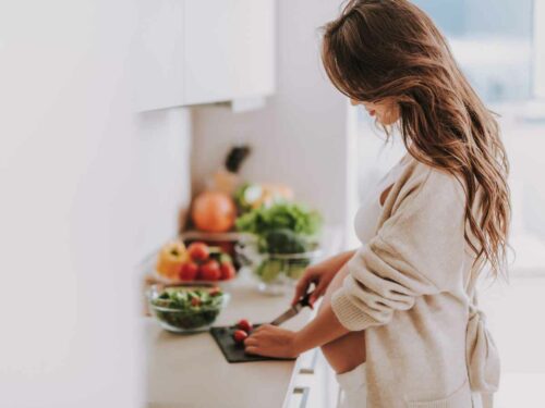 Grávida preparando a refeição ideial com alimentos que fazem parte da alimentação para gestante.