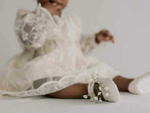 Neném vestindo roupa de batizado e sapatinho, escolhidos pela mãe.
