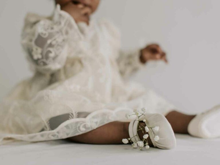 Neném vestindo roupa de batizado e sapatinho, escolhidos pela mãe.