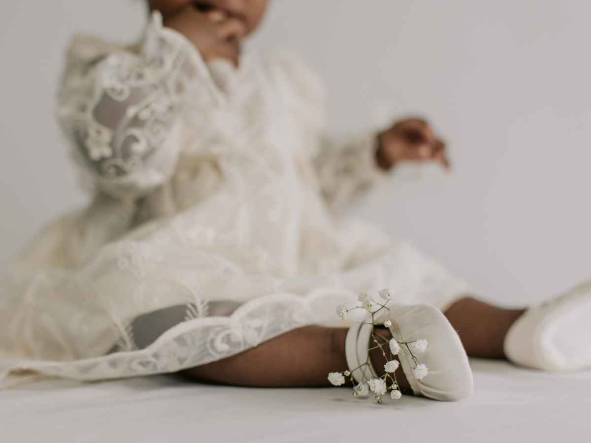Neném vestindo roupa de batizado e sapatinho, escolhidos pela mãe.
