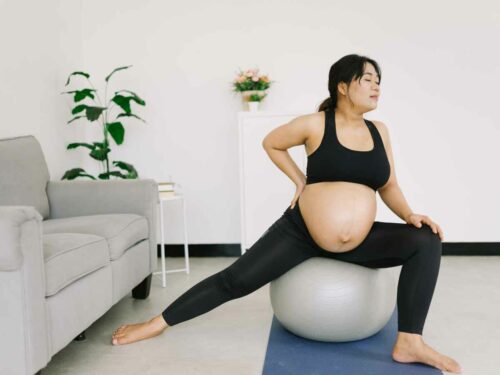 Mulher fortalecendo assoalho pélvico ao praticar yoga na gravidez e realizar o movimento em uma bola de inflar.