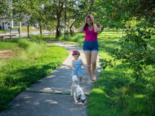 Bebê passeando com o cachorro em um parque, enquanto a mãe observa atentamente, garantindo que o pet mantenha sua rotina habitual mesmo após a chegada do bebê, promovendo equilíbrio e bem-estar para ambos.