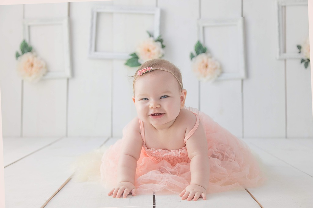 Bebê sorridente com molduras de fotos ao fundo, simbolizando ideia para foto de mesversário