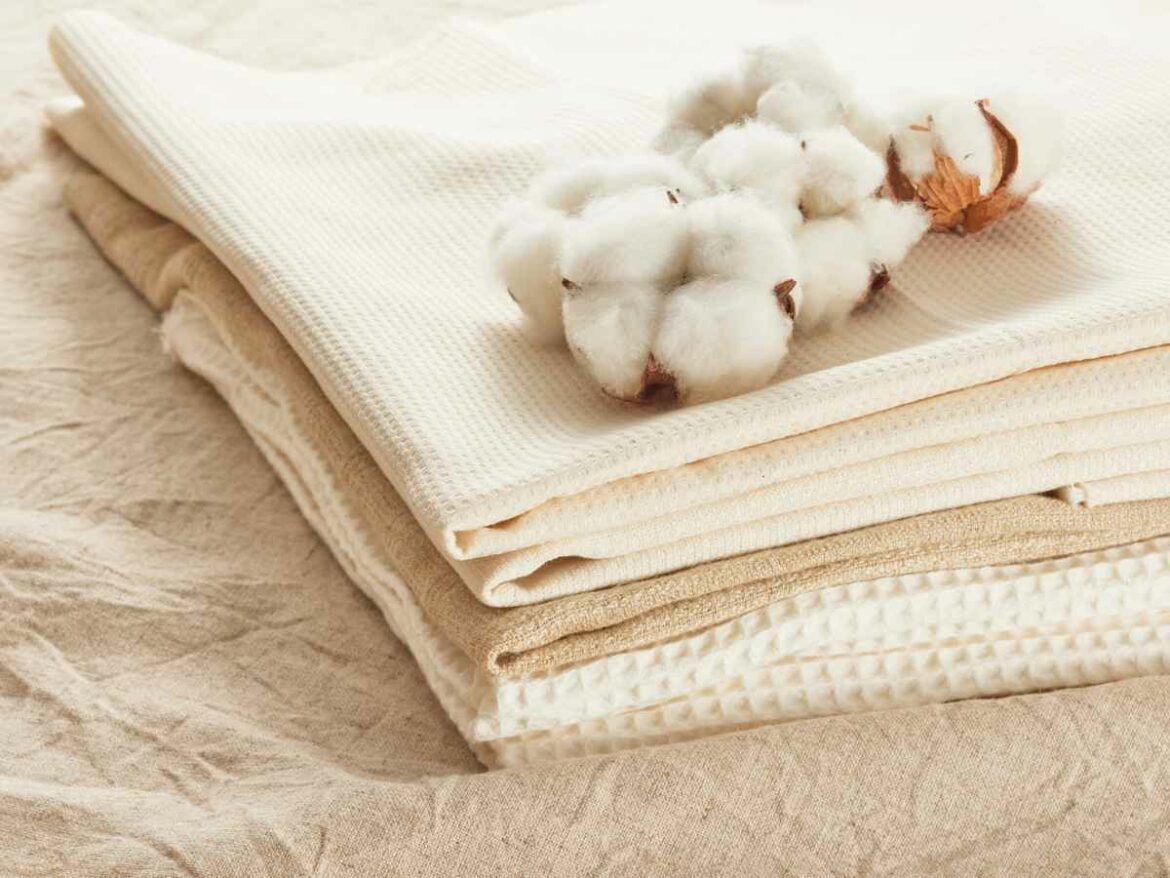 Tecidos de algodão empilhados com a planta de algodão na parte superior