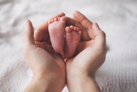 Mãos de mãe segurando os pés de bebê recé-nascido ilustrando como preprar a chegada de um bebê