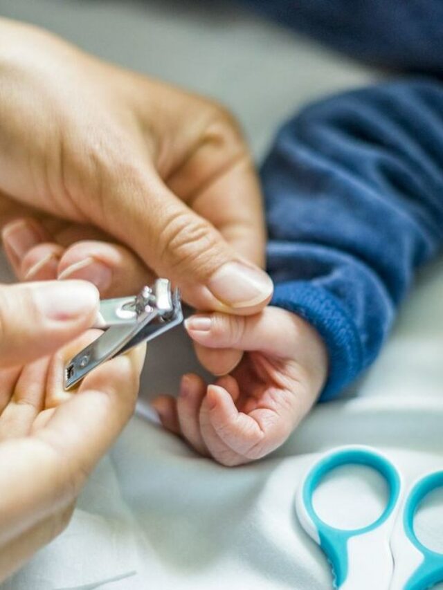 Mãe cortando unha de bebê menino usando tesourinha azul