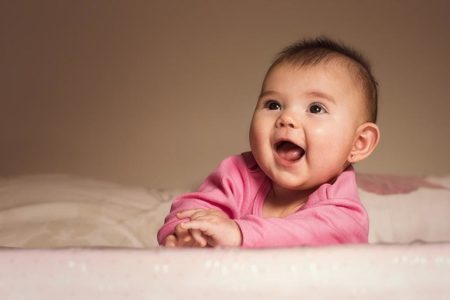 Bebê com soluço com boca aberta e roupinha cor-de-rosa