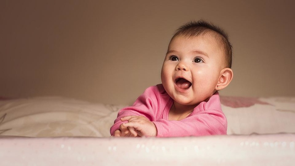 Bebê com soluço com boca aberta e roupinha cor-de-rosa