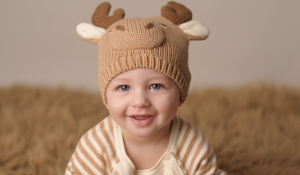 Bebê sorrindo com touquinha de alce