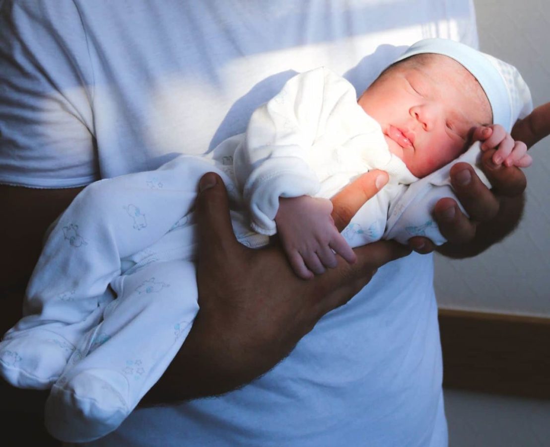 bebê no colo com touca e roupa de algodão para o inverno