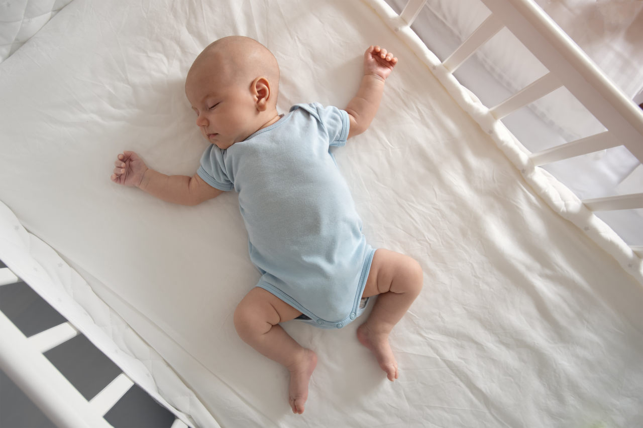 bebê vestido de azul de forma confortável e com estilo em berço