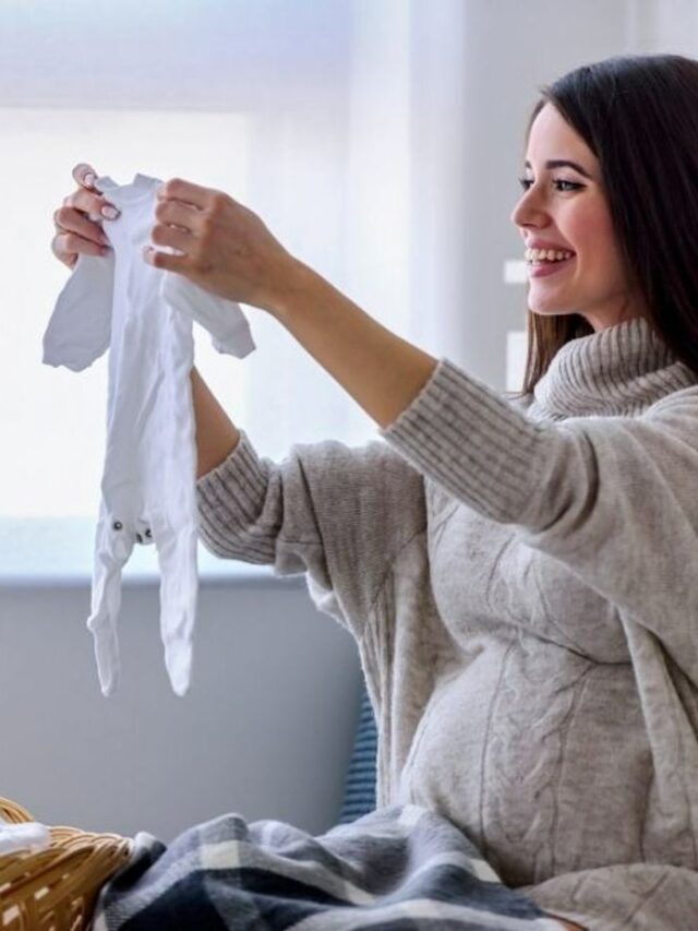 mamãe segurando roupa de bebê após fazer lista de enxoval de bebe menino completa