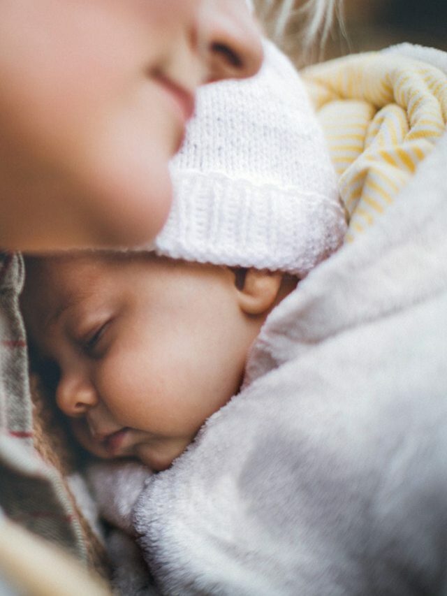 mãe abraçando recém nascido usando roupa de inverno para bebê
