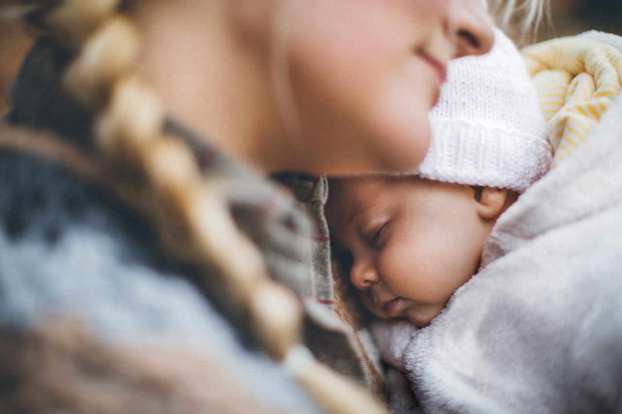 mãe abraçando recém nascido usando roupa de inverno para bebê