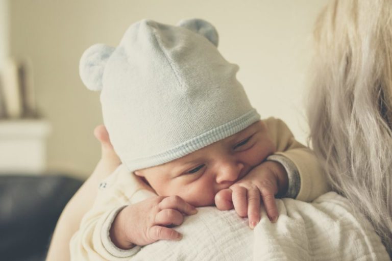 mãe segurando bebê com touca e roupas de inverno para bebe