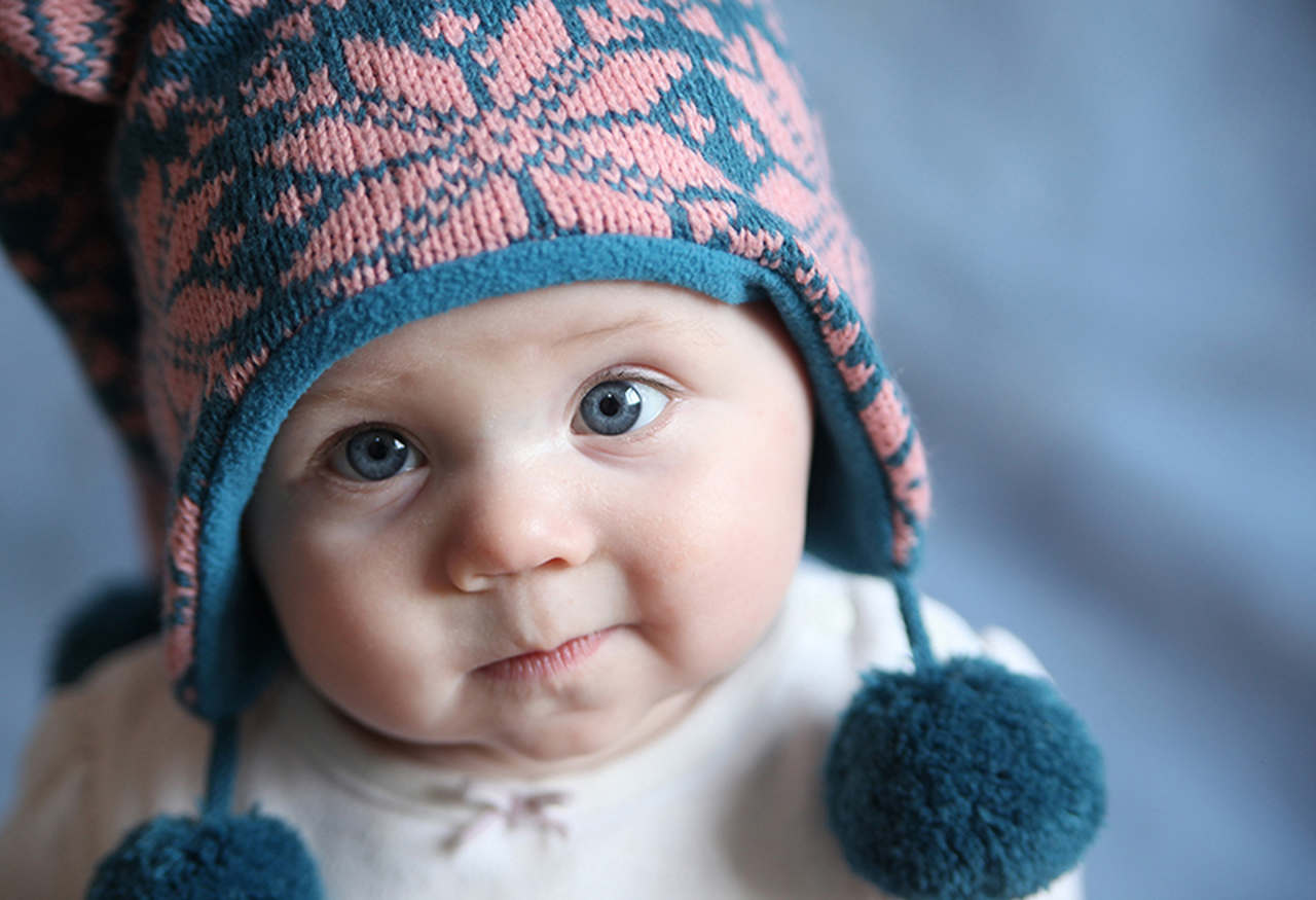 bebe de olhos azuis usando touca e roupas de inverno para bebes
