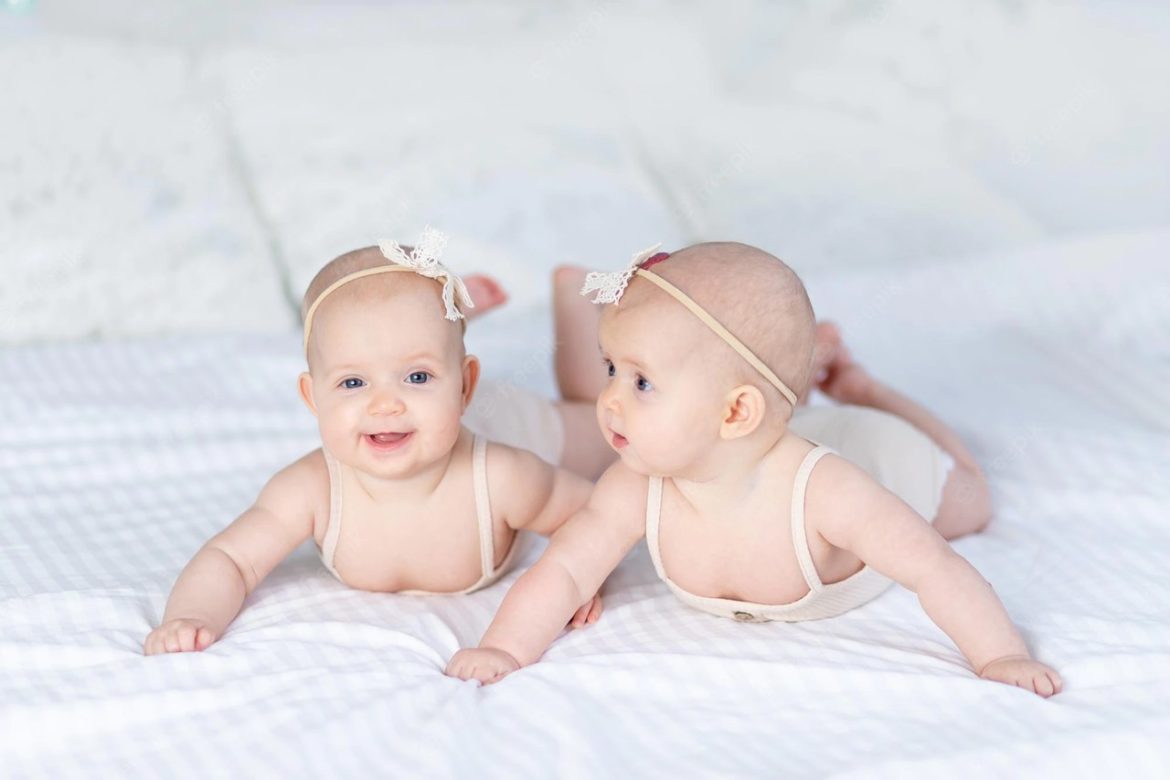 Gemea deitadas de barriga para baixo em lençol