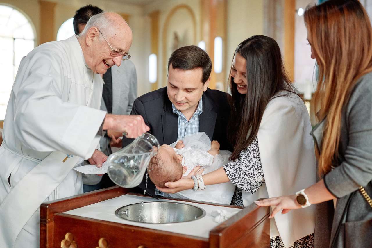 bebê com a família em igreja sendo batizada com roupa para batizado