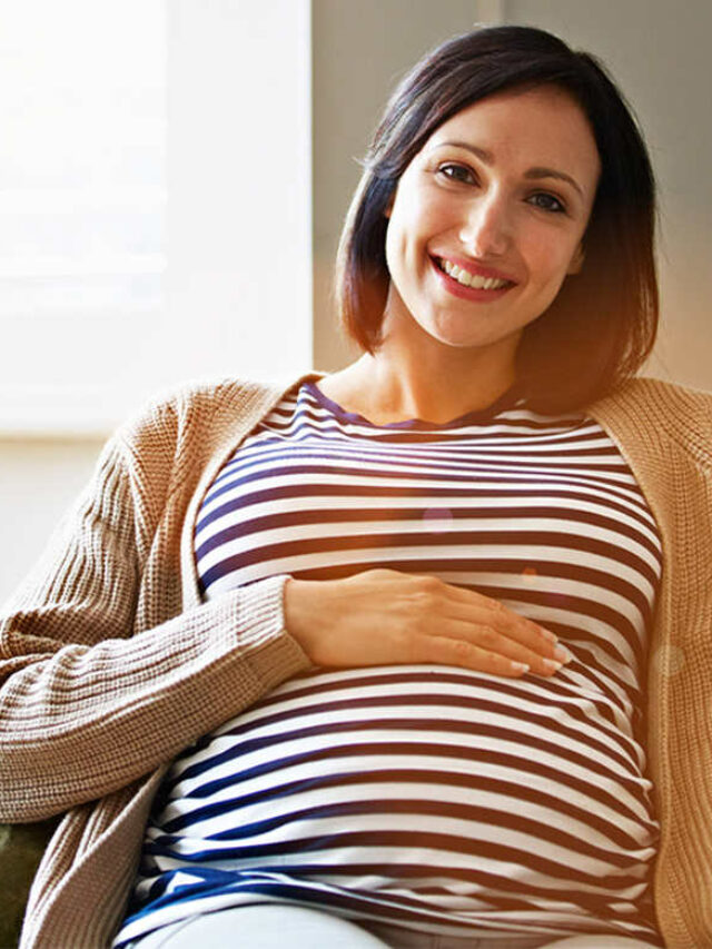 Grávida sorrindo, com a mão sobre a barriga, simbolizando a diferença entre gravidez de menino e menina