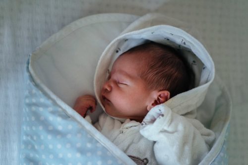 Bebê dormindo envolto em charutinho, representando cuidados com bebê no inverno