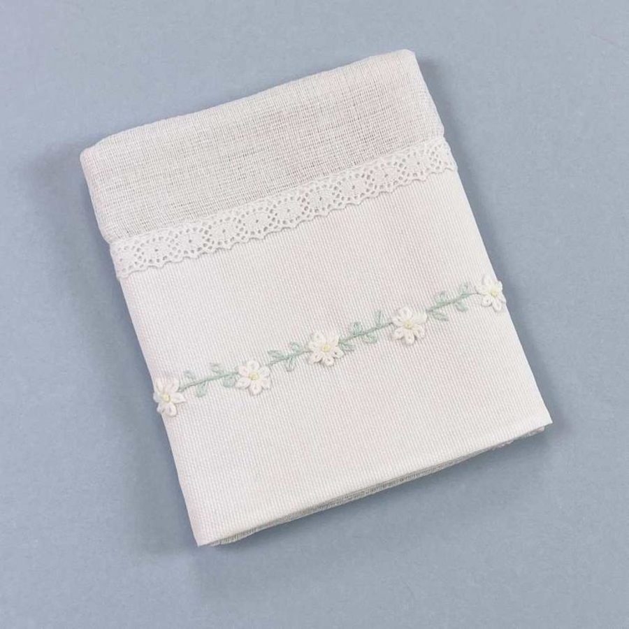 Fralda de pano branca com pequenas flores bordadas, se trata de uma fralda de pano da marca Laleblu