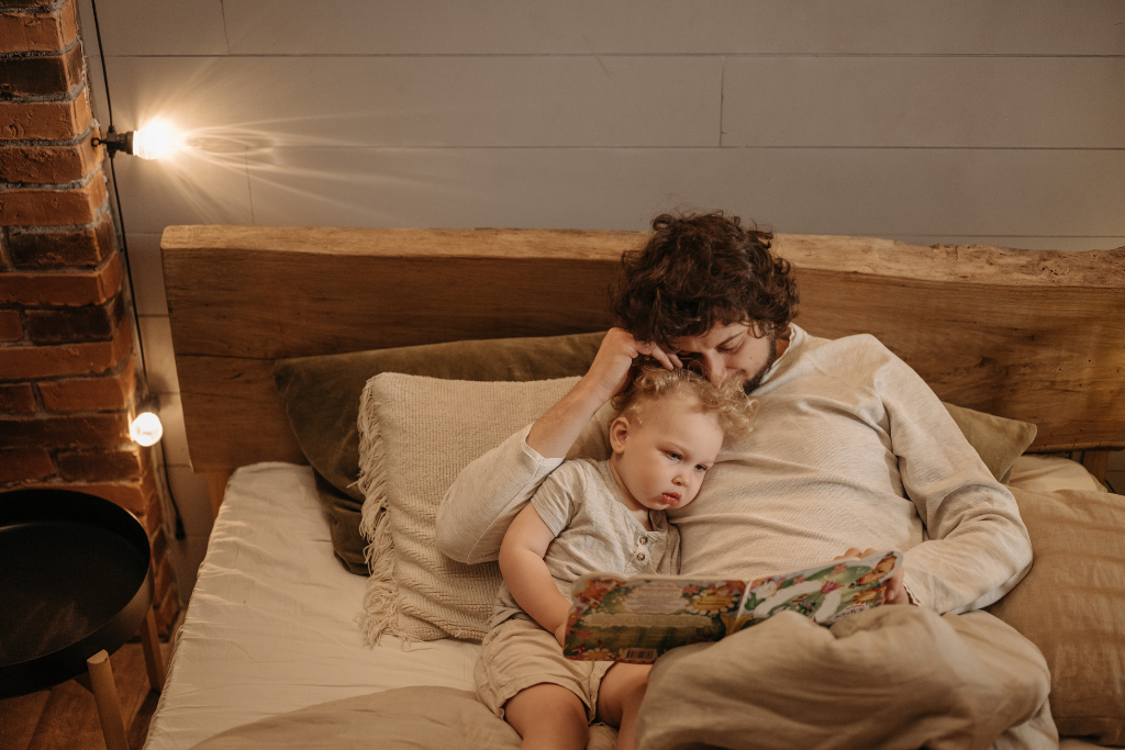 Pai e filho deitados na cama lendo um livro