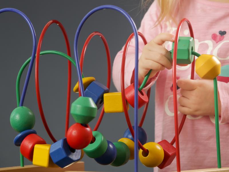 bebê com brinquedo colorido e diversas formas para desenvolver a coodenação