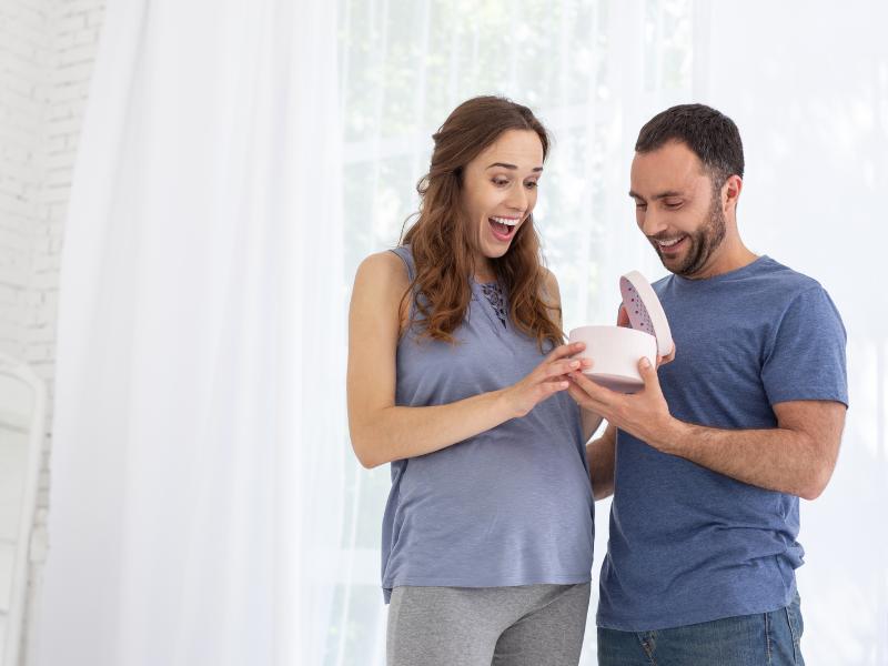 mulher grávida feliz recebendo presente de seu marido