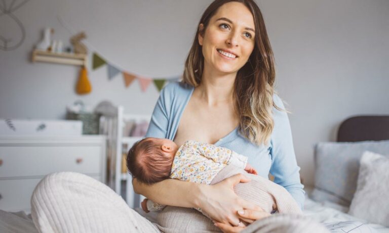 Mãe sentada amamentando seu bebê, beço ao fundo. É seguro amamentar estando doente? espaço amamentação