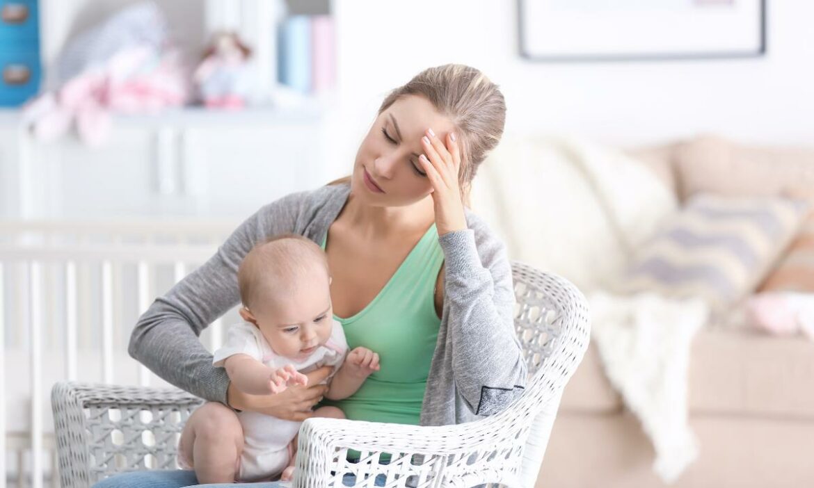 mãe sentada com expressão de preocupação, com seu bebê no colo