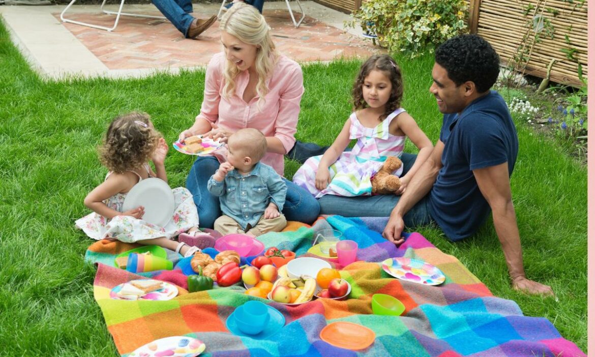 Pai e mãe com filhos bebês fazendo um piquenique com uma bela mesa com frutas
