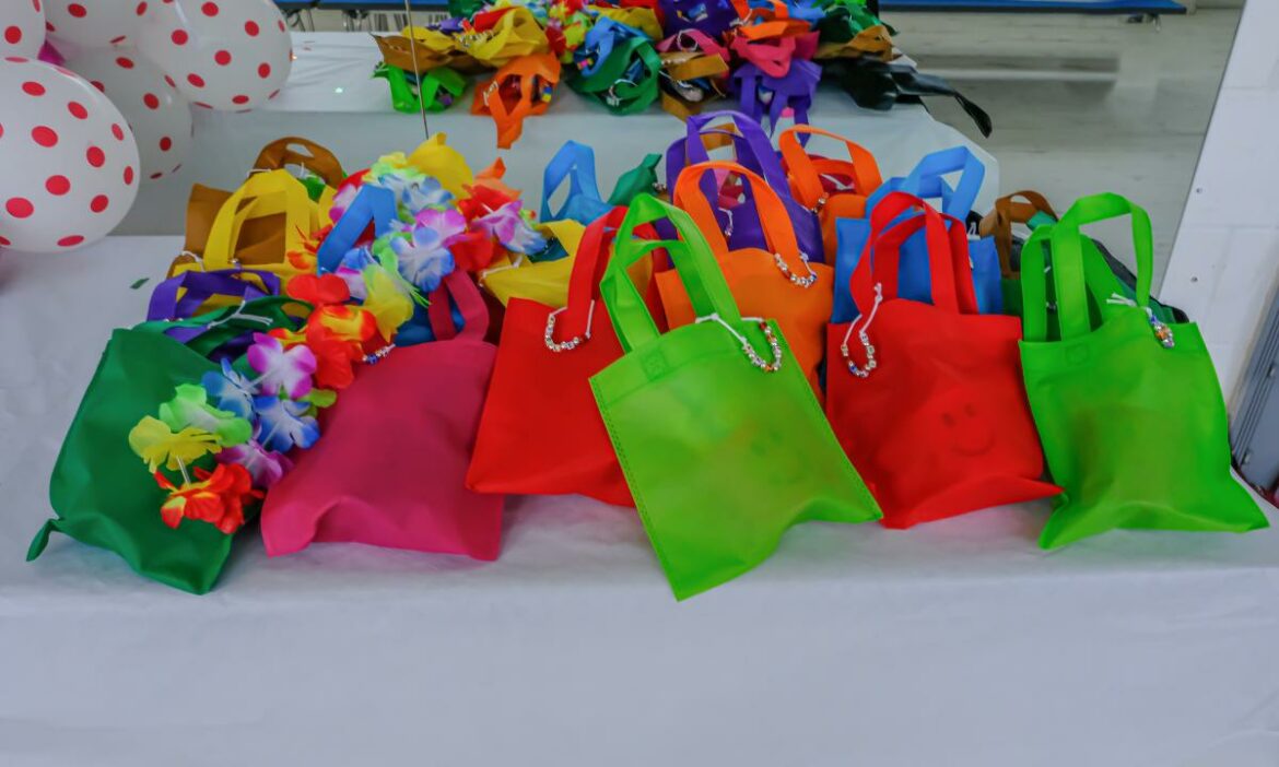várias sacolinhas surpresa para festas de aniversário de bebês coloridas sobre a mesa e algumas bexigas ao lado
