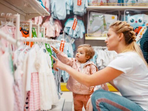 Mãe escolhendo junto de sua filha qual roupinha de Páscoa ela vai comprar na loja da Laleblu.