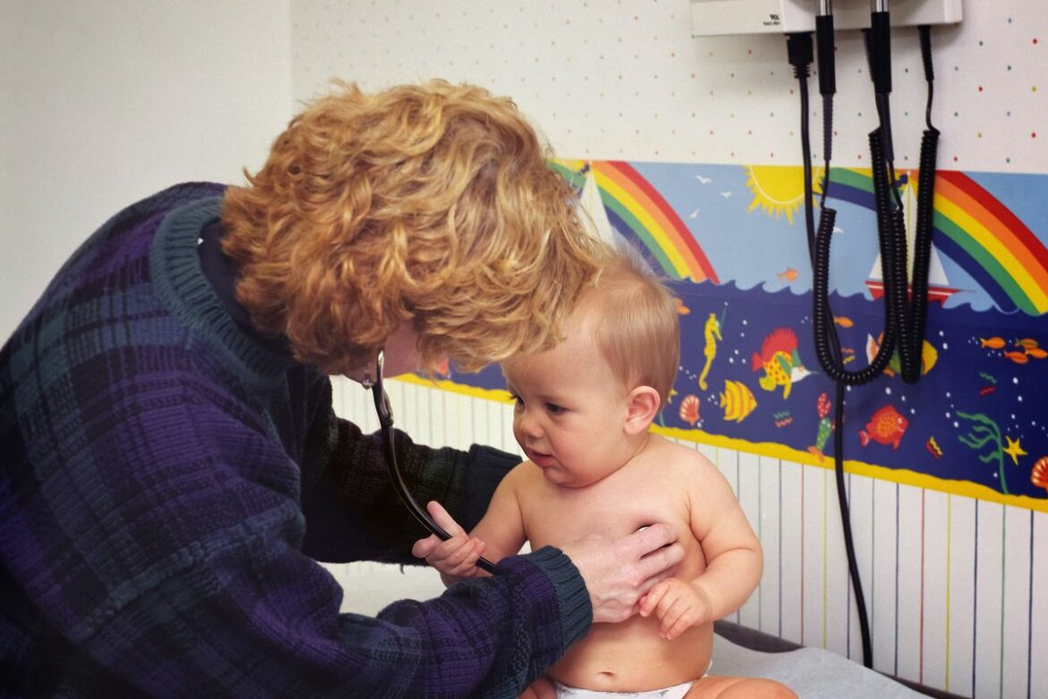 Imagem de uma pediatra examinando um bebê em consulta.