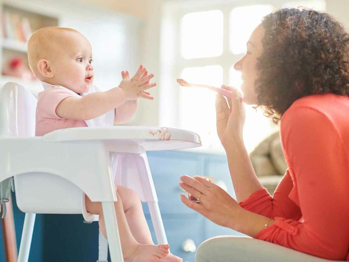 Cuidadora alimentando bebê com gelatina transparente colorida e saborizada com frutas.