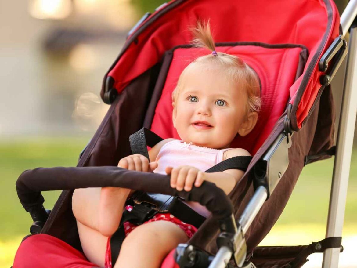 Bebezinha passeando de carrinho em parque.