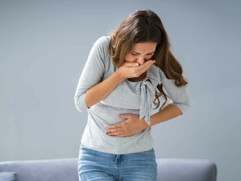 Mulher enjoada após sentir cheiro de comida desagradável, um dos sintomas iniciais da gravidez.