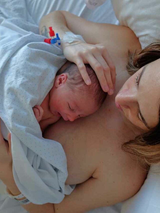 Mulher segurando seu filho após lhe dar a luz através do parto humanizado.