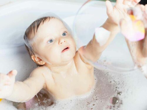 Bebê brincando com bolha de sabão no banho.