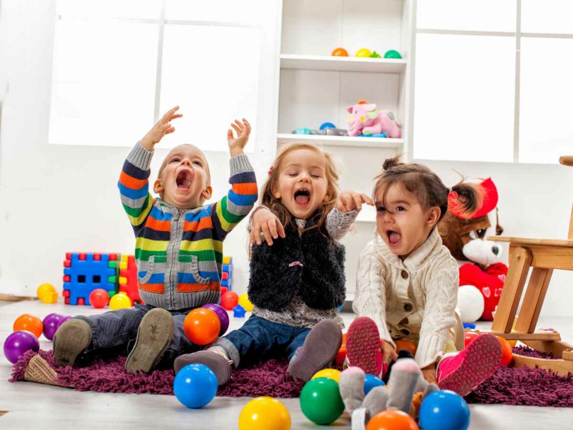 Crianças brincando em grupo em uma sala de brinquedos, enquanto se desenvolvem socialmente e aprendem a identificar emoções.