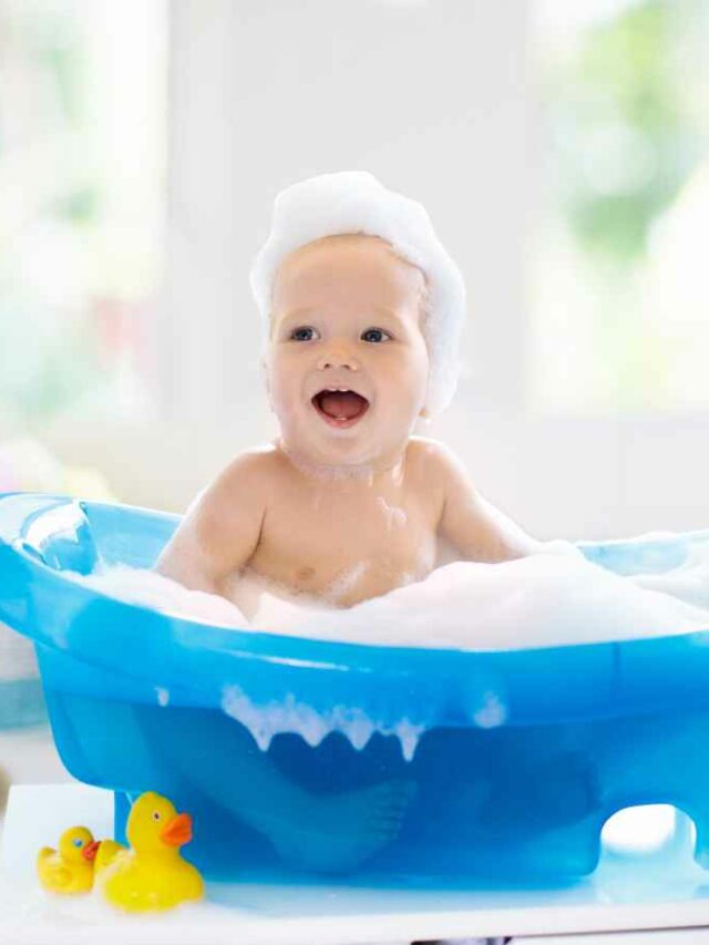 Bebê na hora do banho se divertindo com a espuma da banheira e os brinquedos aquáticos.