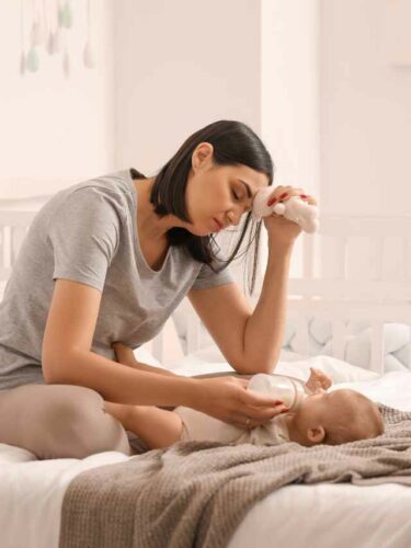 Mãe cuidando do seu filho no puerpério, cansada de tantas tarefas.